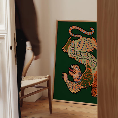 A framed art print featuring a stylized, colorful illustration of two leopards on a dark green background, leaning against a wall in a modern interior setting.