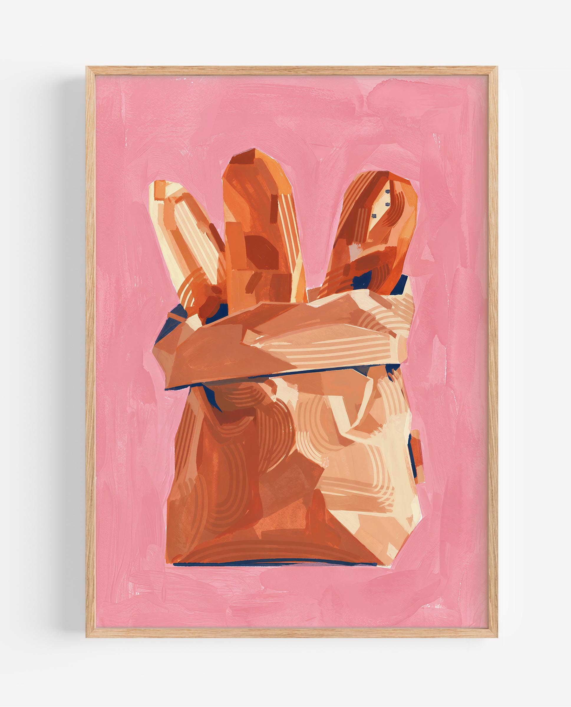 A framed art print featuring a stylized illustration of two baguettes in a brown paper bag against a solid pink background, enclosed in a light wood frame.