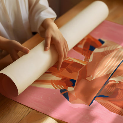 A person unrolls a large cream-colored sheet over an abstract painting featuring warm peach, orange, and pink tones on a wooden table.