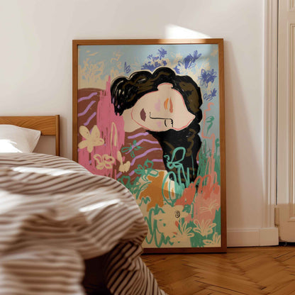 A framed art print featuring a stylized illustration of a woman with dark hair, set in a bedroom next to a bed with striped bedding.