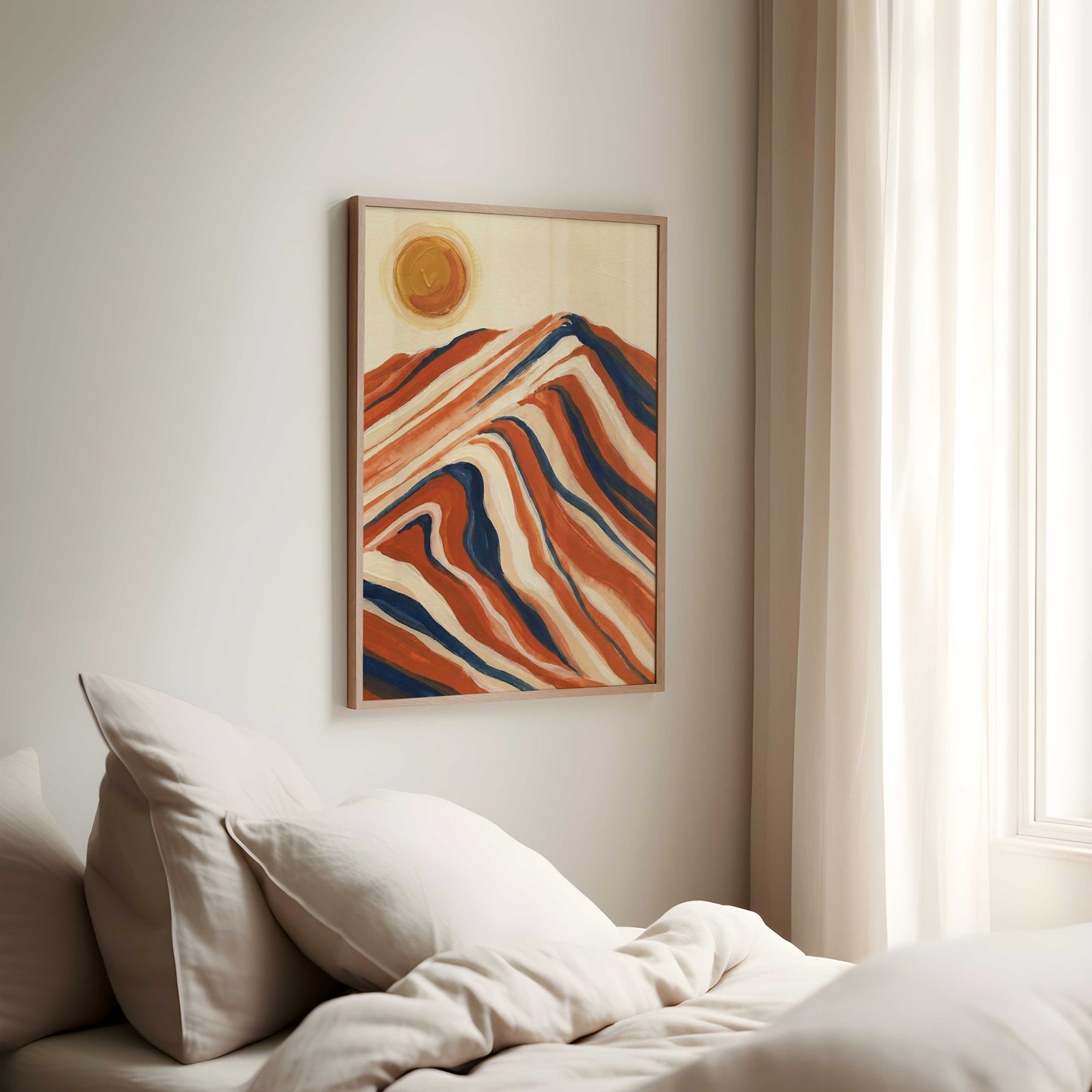A framed abstract landscape art print featuring wavy orange, red, and blue mountain-like lines with a yellow sun on a cream background, hanging on a light gray wall above a bed with beige bedding and pillows.