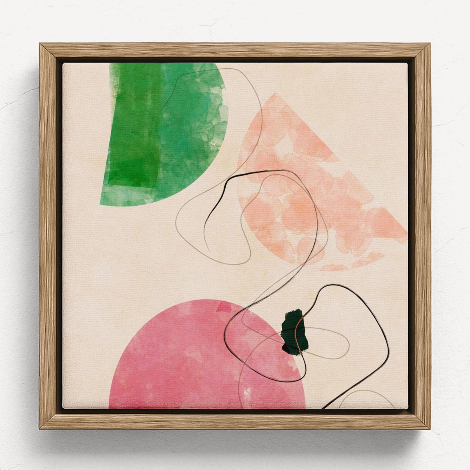 Framed abstract wall art featuring watercolor-like green and pink shapes with thin black curved lines on a light beige background, shown in a natural wood frame against a white wall.