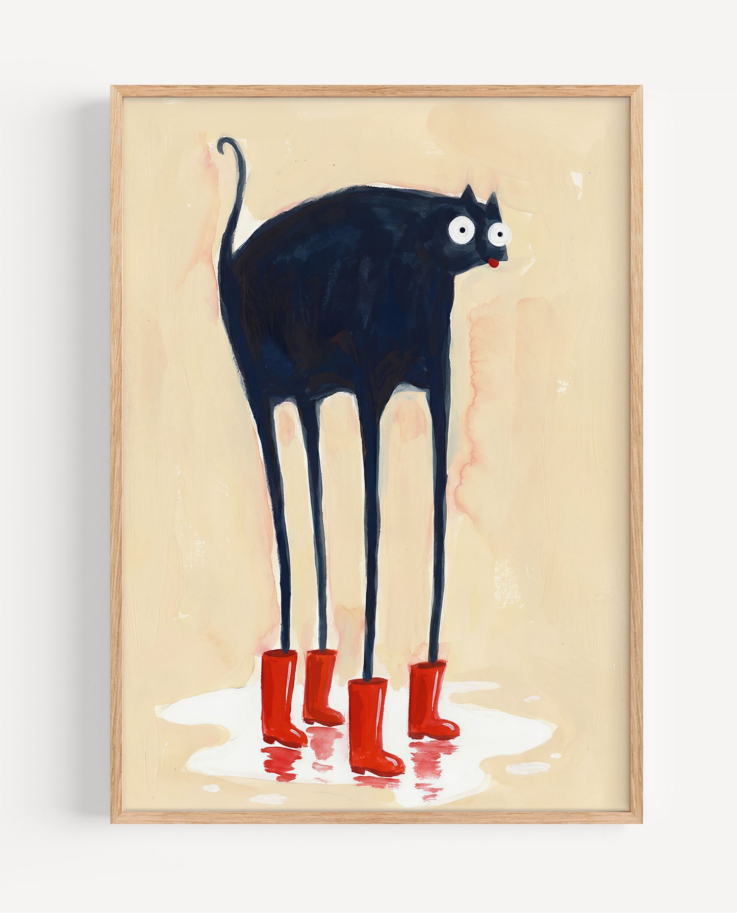 A framed art print featuring a whimsical illustration of a tall black cat with long legs wearing red rain boots, standing on a light beige background. The print is housed in a light natural wood frame and is shown hanging on a plain white wall.