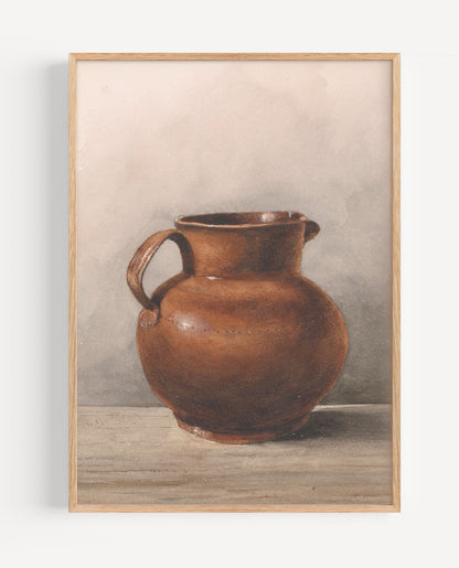 A framed still life art print depicting a brown ceramic pitcher on a tabletop against a neutral gray background, enclosed in a light wood frame.