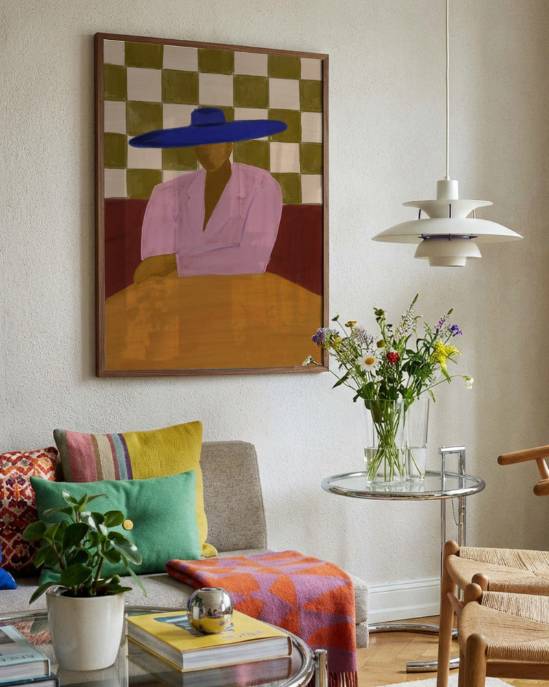 Living room with colorful decor, including a painting of a person wearing a blue hat, a sofa with multicolored pillows, and a small round table with flowers.