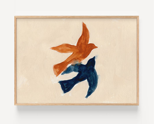 Framed abstract wall art featuring two birds in flight, one in burnt orange and the other in deep navy blue, painted on a textured cream background with a light natural wood frame.