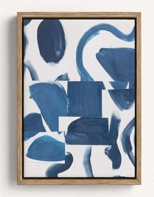 Framed abstract wall art featuring expressive blue brushstrokes and blocks on a white background, enclosed in a light natural wood frame against a white wall.